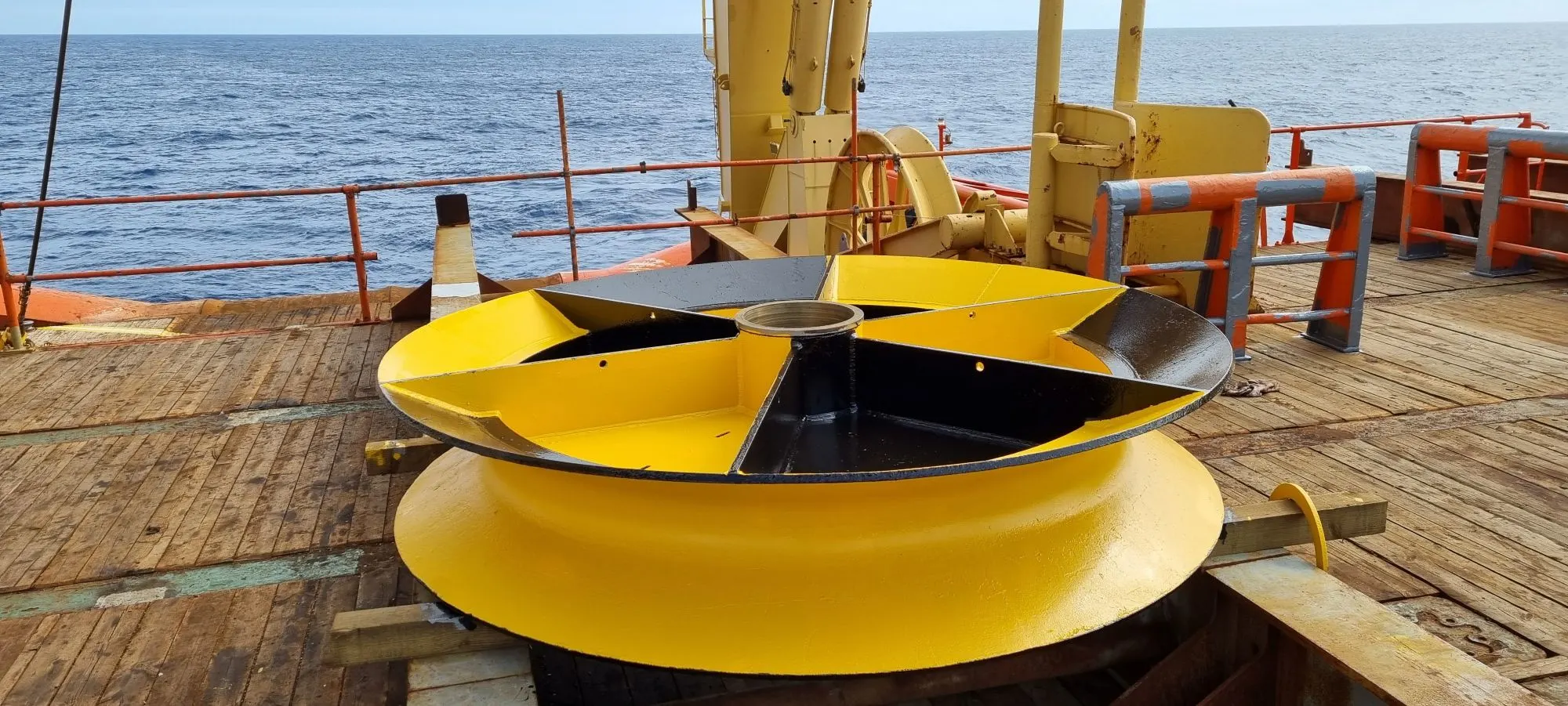 Marine sheave on a ship deck which is painted yellow and black.